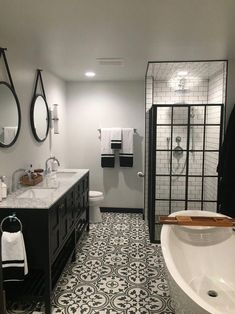 a bathroom with black and white tile flooring next to a bathtub in the corner