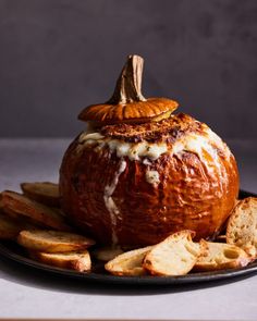 a plate with bread and crackers on it next to a pumpkin shaped cheese ball