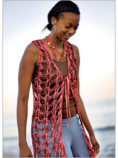 a woman standing on the beach wearing a red crochet top