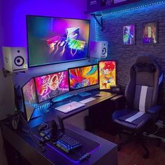 a computer desk topped with three monitors and a keyboard next to a monitor on a wall