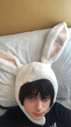 a person laying in bed wearing a bunny ears hat