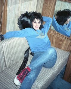 a woman sitting on a couch with her hair in the air