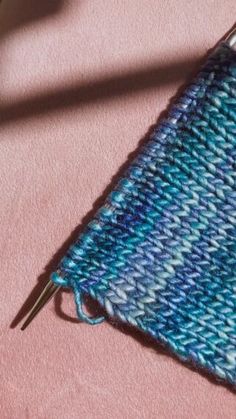 a blue and white knitted pouch sitting on top of a pink surface next to a pair of scissors