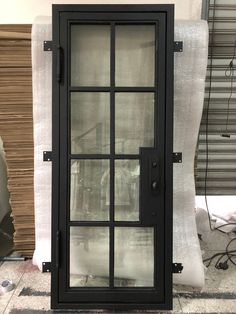 a black door with glass on the outside and inside, in front of a pile of fabric