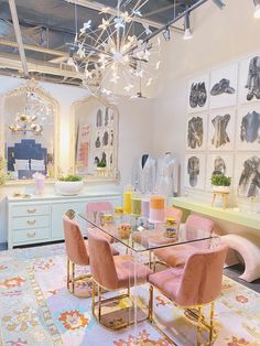 a dining room table with pink chairs and chandelier hanging from the ceiling above it