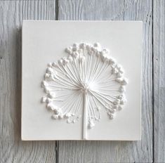 a white tile with an intricate design on the outside of it, mounted on a wooden wall