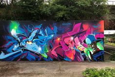 a large colorful graffiti wall next to some bushes