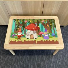 a wooden table with an image of gnomes in the woods on it and a mushroom house