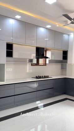 an empty kitchen with white and grey cabinets, black counter tops and ceiling fan in the middle