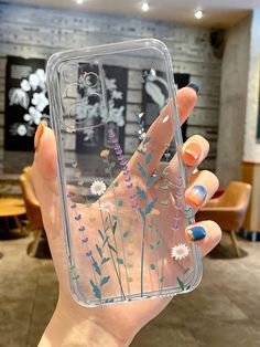 a woman holding up a clear case with flowers on it