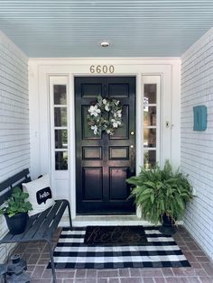 a black and white checkered rug on the front porch with potted plants next to it