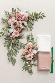 two napkins with flowers and greenery on them next to an empty napkin holder