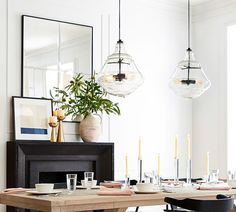 a dining room table is set with place settings and plates, candles, and vases