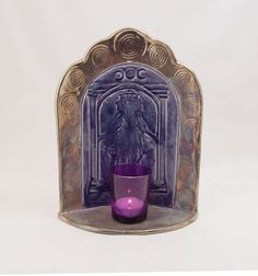 a purple glass cup sitting in front of a wall