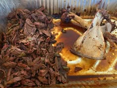 a metal container filled with lots of food next to a pile of meat on top of a table