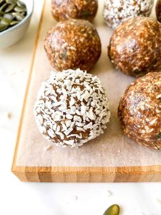 several balls of food sitting on a cutting board next to some seeds and a bowl