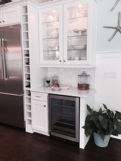 a kitchen with white cabinets and stainless steel refrigerator freezer combo in the center, next to a potted plant