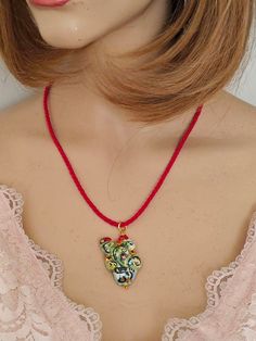 Red silk rope necklace with prickly pear pendant in Caltagirone ceramic, handmade and painted, with 22 kt gold leaf applications, 3.5 cm in size. Golden brass lobster clasp closure. necklace length 50 cm Red Hand Painted Pendant Necklaces, Handmade Red Enamel Necklaces, Red Handmade Enamel Necklaces, Handmade Red Enamel Necklace, Pear Pendant, Ceramic Handmade, Prickly Pear, Rope Necklace, Red Silk