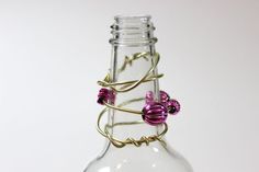 a glass bottle with some wire wrapped around it's neck and flowers in the bottom