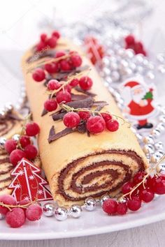 a roll with chocolate and raspberries is on a plate next to christmas decorations