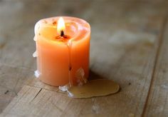 an orange lit candle sitting on top of a wooden table