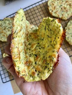 someone holding up a piece of bread that has been cut in half and is sitting on a cooling rack