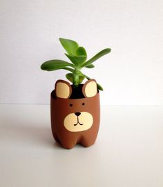 a brown bear planter with a green plant in it's mouth on a white surface