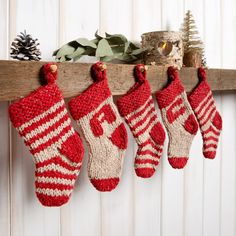 three knit stockings hanging from a wooden shelf