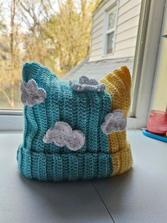 a knitted hat sitting on top of a window sill next to a house