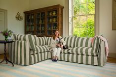 a woman sitting on a striped couch with her dog