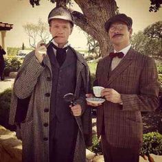 two men dressed in old fashioned clothing standing next to each other holding cups and spoons