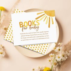 a white plate topped with yellow flowers next to a card that reads books for baby