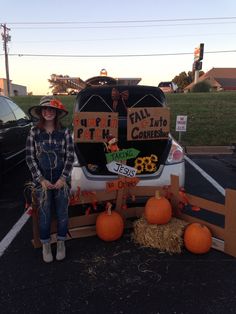 a woman standing in front of a car decorated with pumpkins and other decorations for halloween