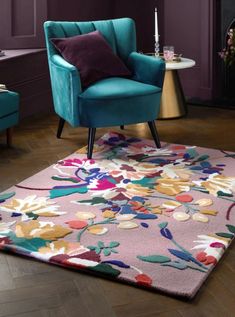 a blue chair sitting on top of a wooden floor next to a pink rug and purple walls