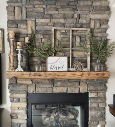 a stone fireplace with candles and greenery on top