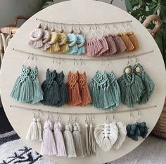 several tasseled earrings hanging on a circular white rack with plants in the background