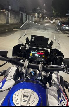 a close up of the handlebars on a motor bike at night time with lights in the background