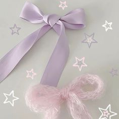 a pink ribbon and some stars on a white table with pastel purple ribbons in the background