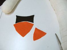 an orange and black piece of fabric next to scissors on top of a white surface