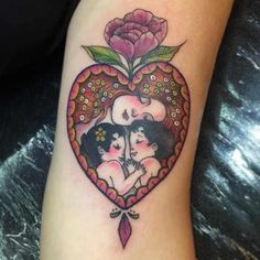 a heart shaped tattoo with two women and a flower on the side of the arm