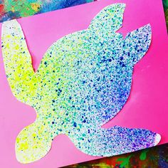 a paper cut out of the shape of a bird with paint splattered on it