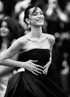 a woman in a strapless dress smiles as she stands on the red carpet at an event