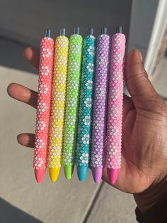 four different colored pens in the palm of someone's hand, all lined up