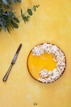 a cake sitting on top of a yellow table next to a knife and planter