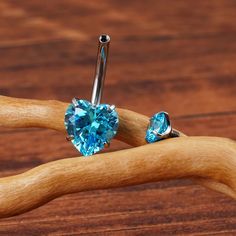 a pair of blue heart shaped piercings on a wooden stick