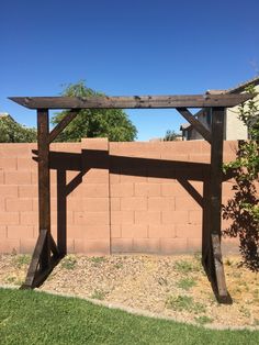 a wooden bench sitting in the middle of a grass covered yard next to a brick wall