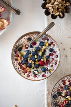 two bowls filled with oatmeal and fruit on top of a white table