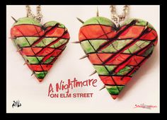 two red and green heart shaped necklaces with spikes attached to each other on a chain