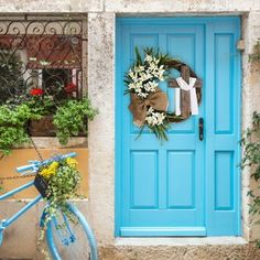 a blue bicycle is parked in front of a blue door with a wreath on it