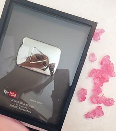 a person holding a cell phone in their hand with pink crystals around it and the reflection of a woman's face